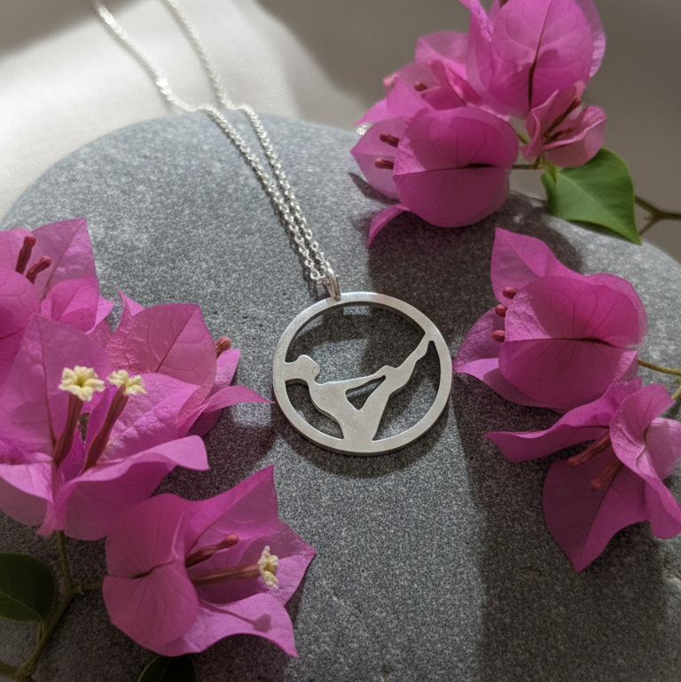 Pilates Teaser sterling silver necklace displayed on a stone with flowers around.